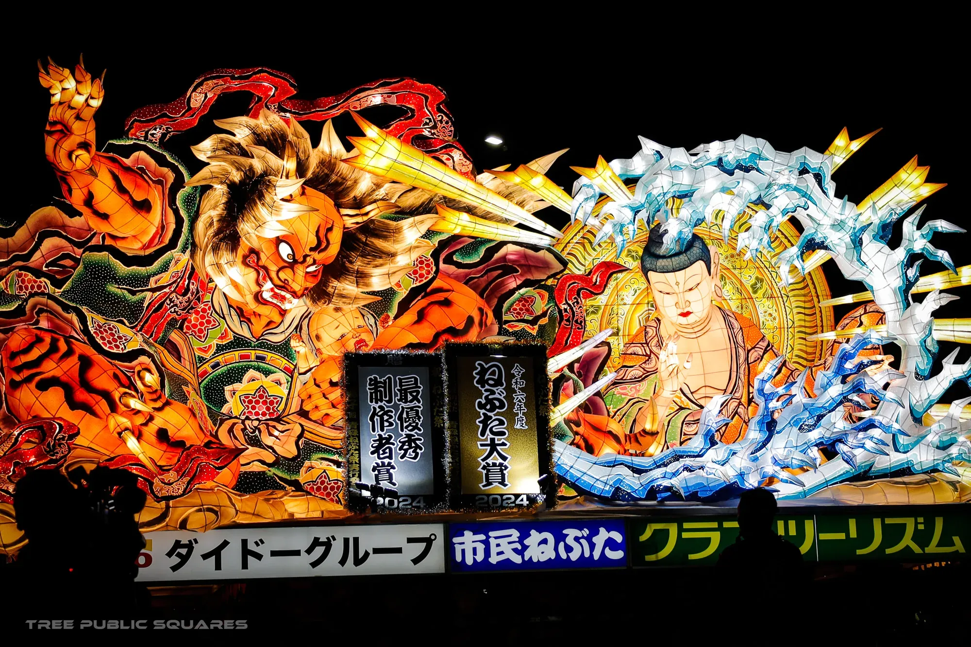 A giant illuminated Nebuta float of a fierce red demon at night, Aomori