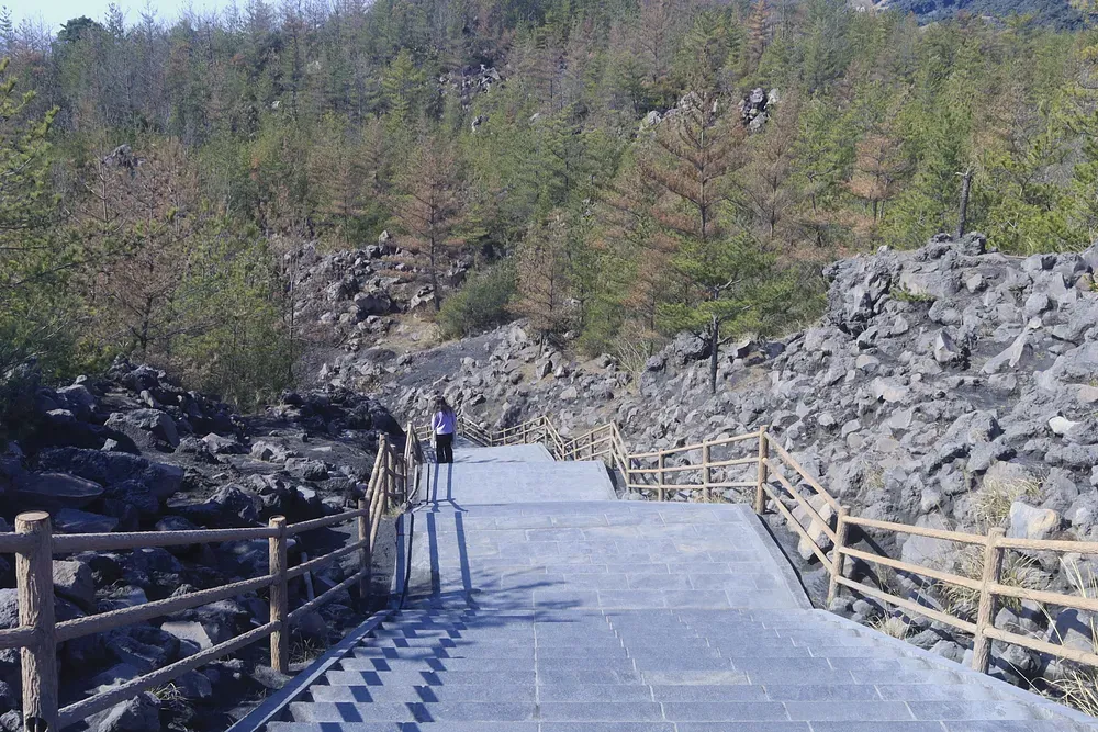 A coastal path beneath the ash-grey slopes of Sakurajima